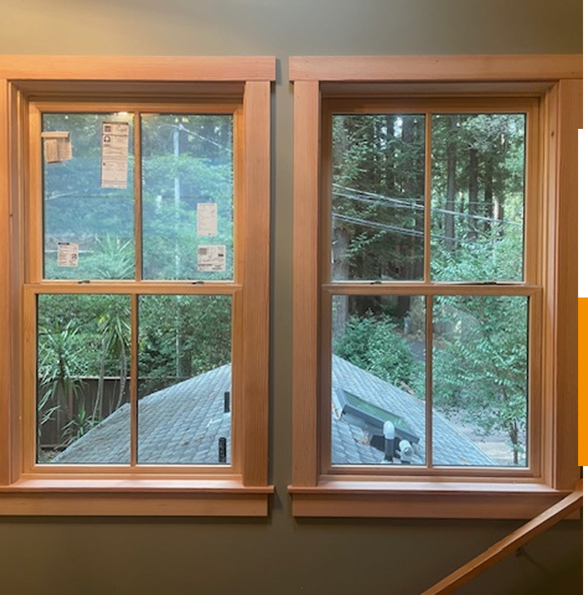 Two windows overlooking trees and rooftops.